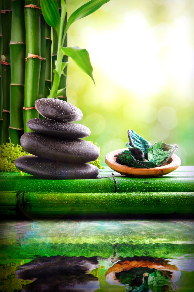 Black,Stones,Stacked,And,Bowl,With,Green,Leaves,Reflected,In