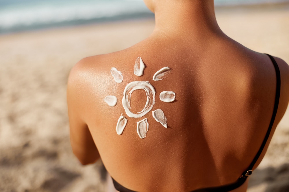 Woman,Applying,Sun,Cream,On,Tanned,Shoulder,In,Form,Of